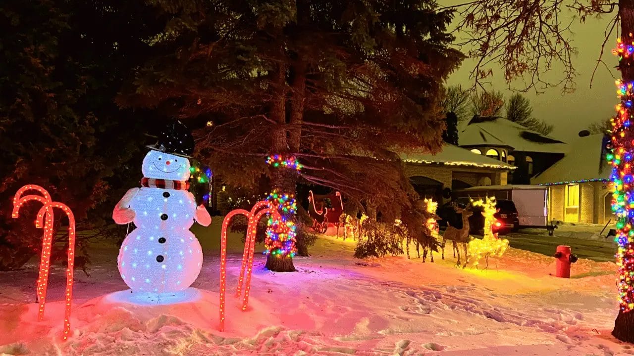 A lit up snowman with candy cane and reindeer lights.